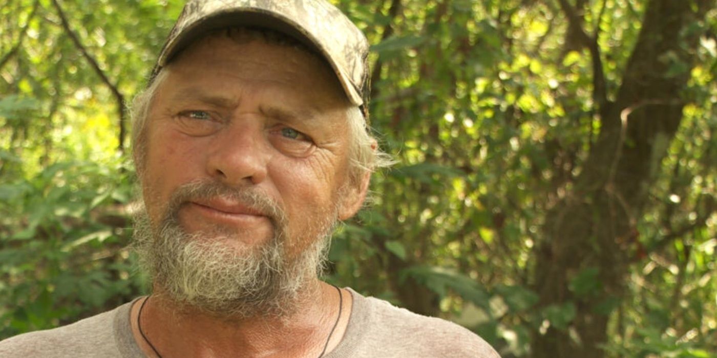 Junior Edwards from Swamp People wearing a camo baseball cap and looking at the camera, standing outdoors.