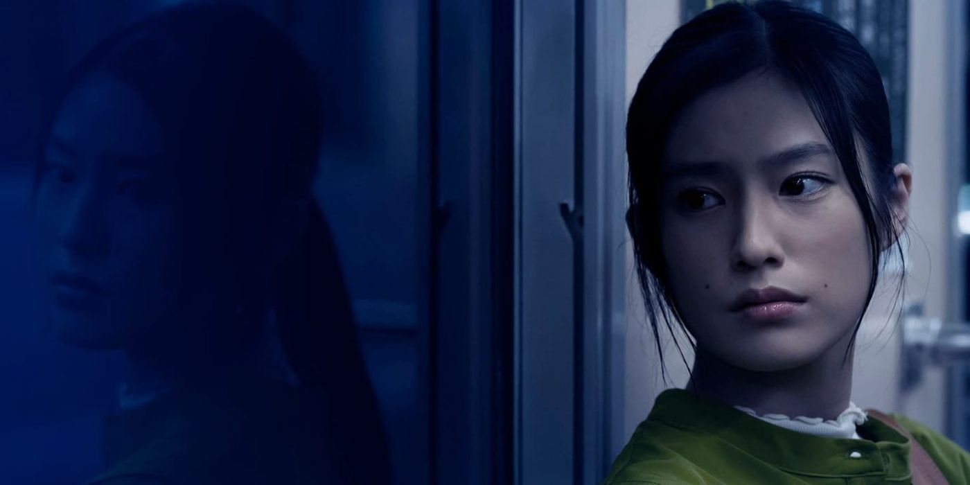 Yuri Tsunematsu sitting on a train and looking to her right while her reflection can be seen in the window, in Kisaragi Station