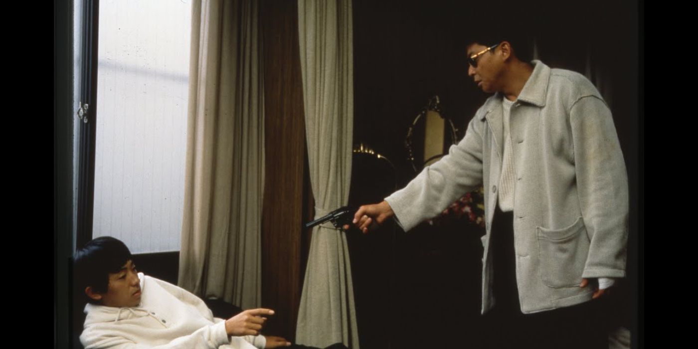 A man pointing a gun at a scared man in a chair in Kiyoshi Kurosawa&rsquo;s Serpent&rsquo;s Path