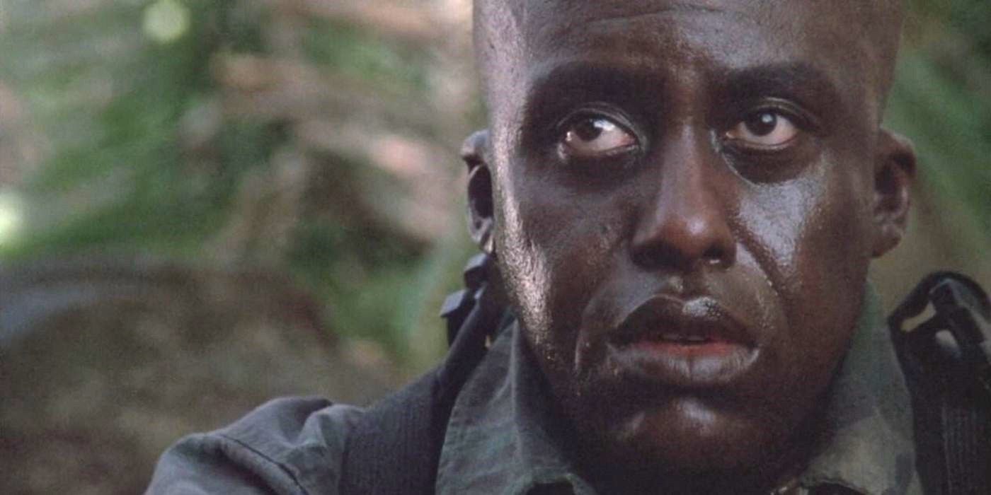 Bill Duke as Mac Eliot looks scared and worried, sitting in a jungle in Predator.