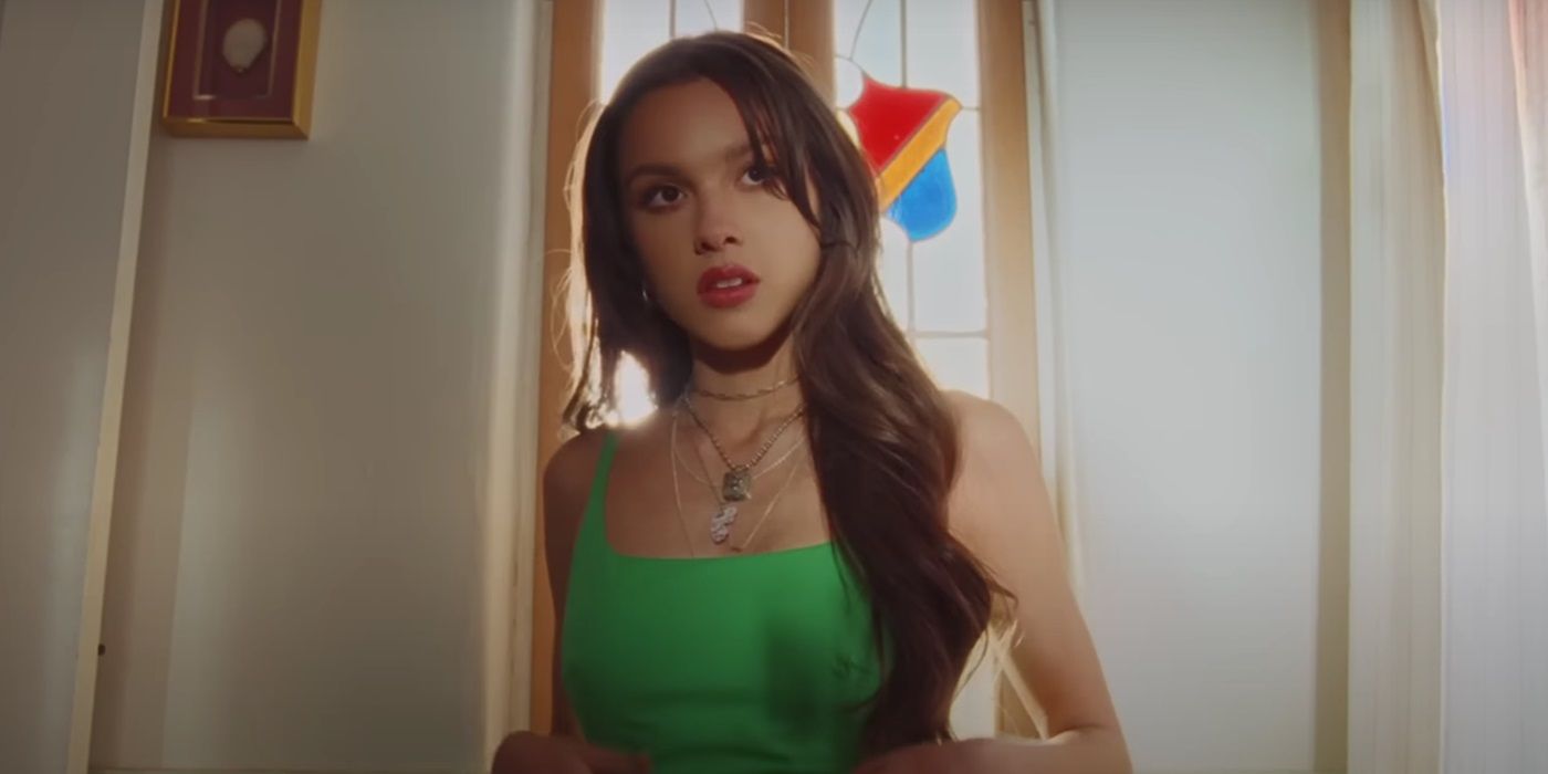 Olivia Rodrigo wearing a green dress in the music video for &ldquo;deja vu&rdquo;