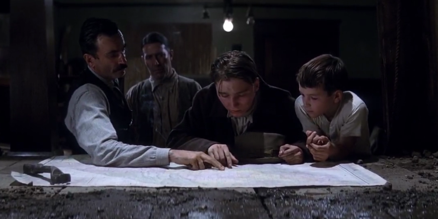 Daniel and Paul point at a map while Fletcher Hamilton and HW look at them in There Will Be Blood.