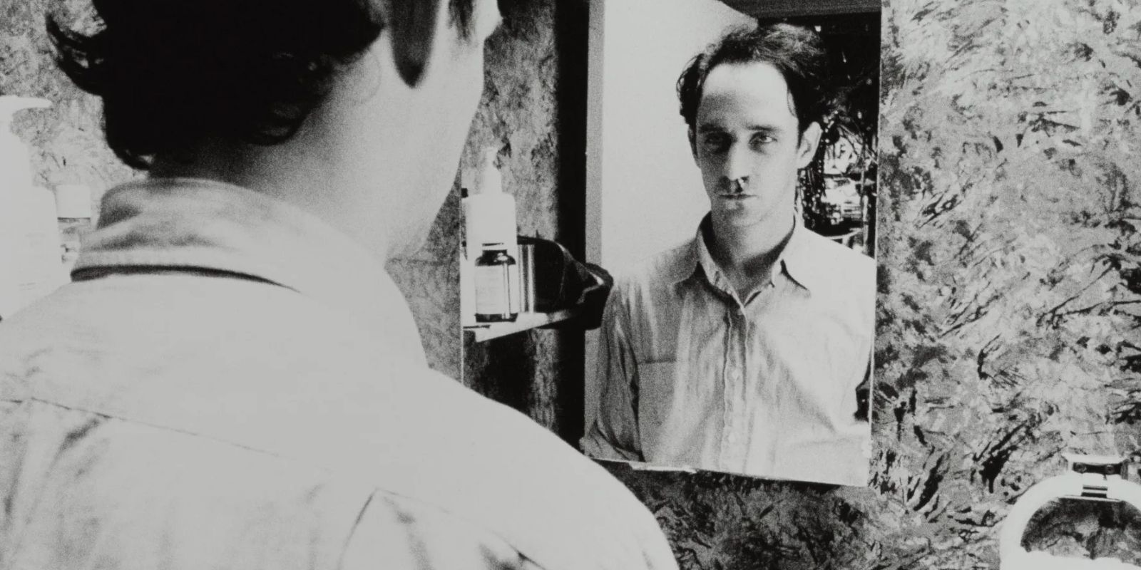 A man with a blood nose looks at himself in the mirror