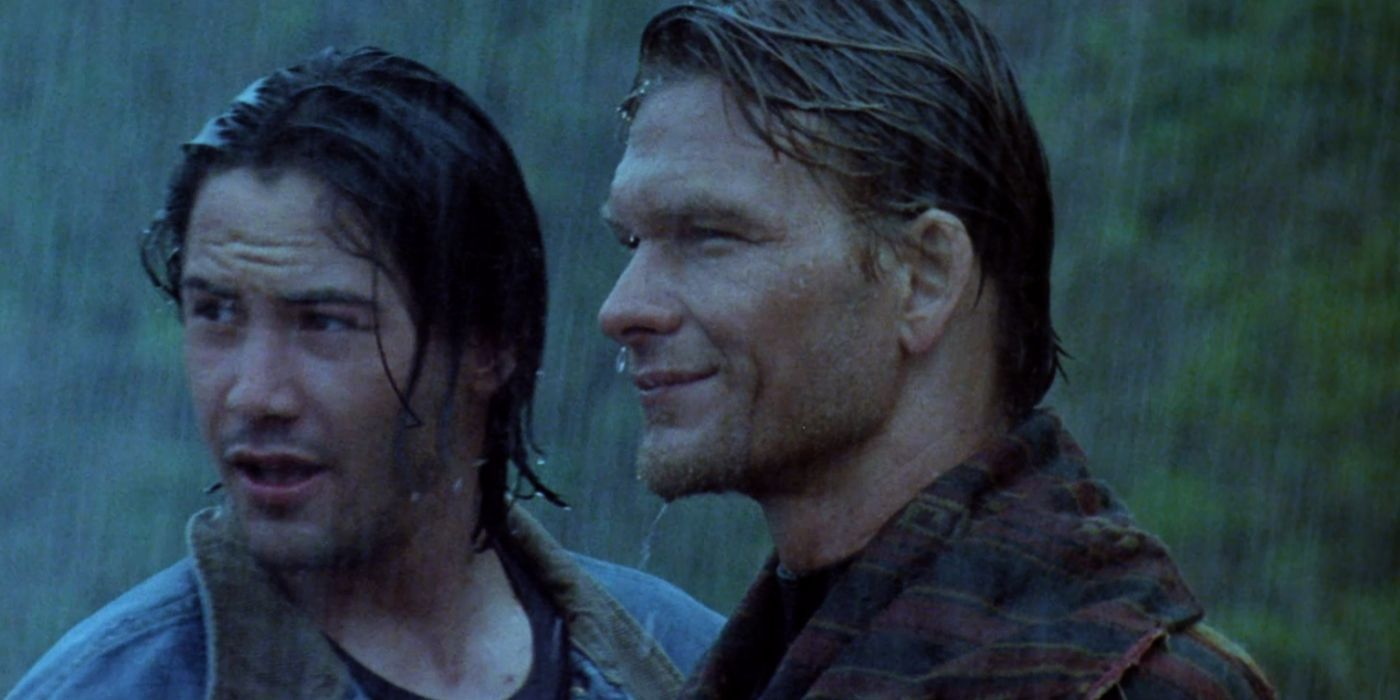Johnny and Bodhi stand together facing the ocean in the 50 year storm in Point Break 1991