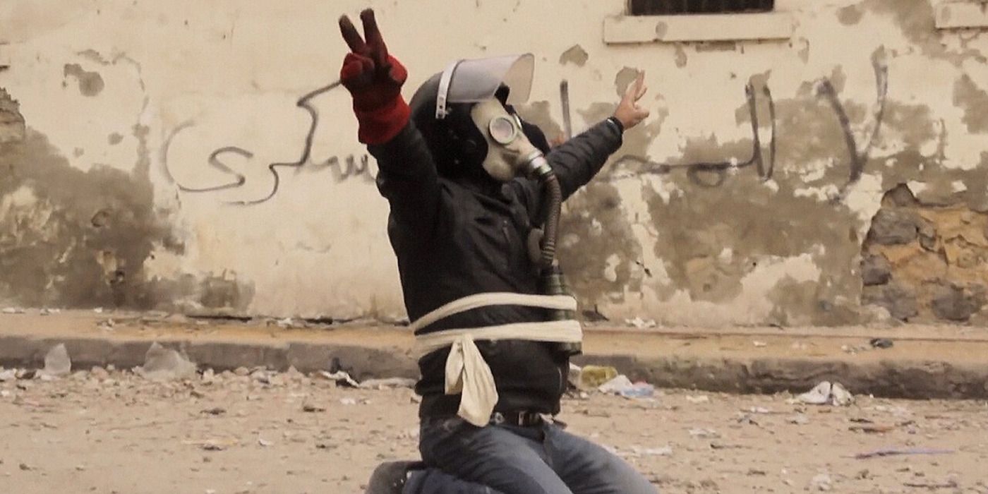 Resistance fighter kneeling and spreading his arms in &lsquo;The Square&rsquo; (2013)