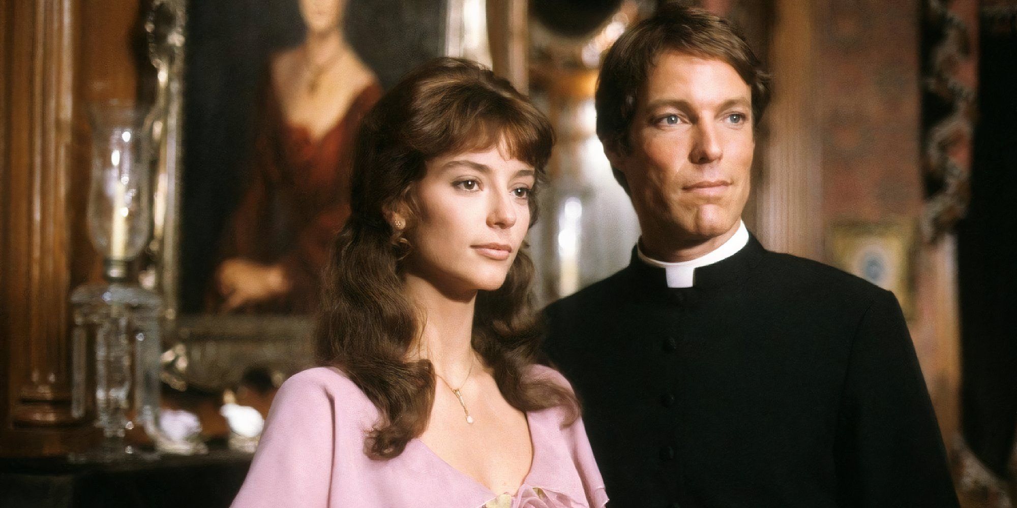 Richard Chamberlain as a priest and Rachel Ward in The Torn Birds smiling softly.