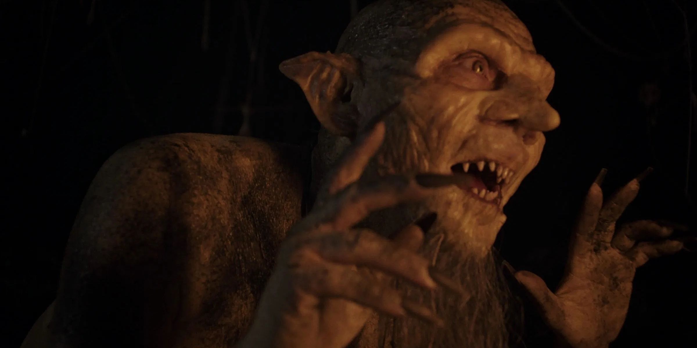 Actor Joss Carter as Rumpelstiltskin, with hideous goblin-like features, holding up his hands and baring his teeth in Rumpelstiltskin.