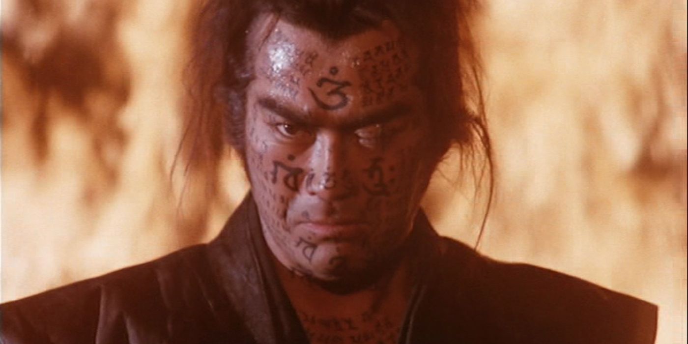 Sonny Chiba looking at the camera with kanji drawn on his face and fire roaring behind him in Samurai Reincarnation