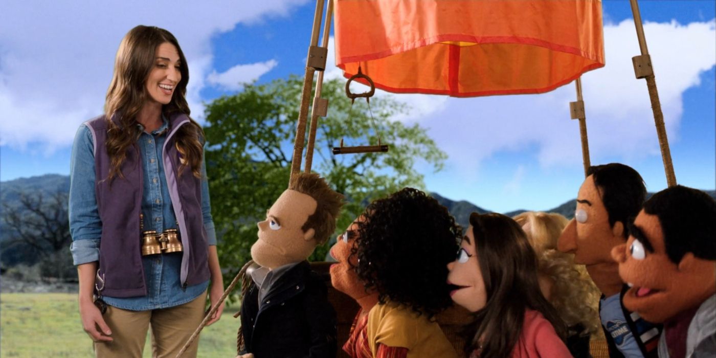 Sara Bareilles singing and smiling down at puppet versions of the study group in front of a hot air balloon in &ldquo;Community.&quot;