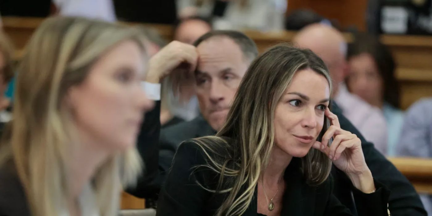 Karen Reed wearing a black suit sitting down in court smiling in &lsquo;The Trial of Karen Reed.'