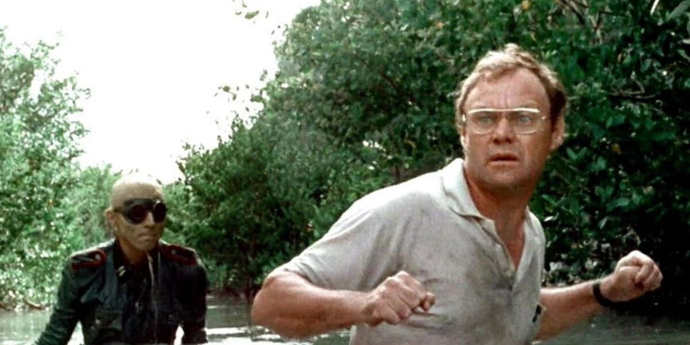 Jack Davidson as Norman, wading through a jungle river tensely, followed by a Nazi zombie in &lsquo;Shock Waves&rsquo;.