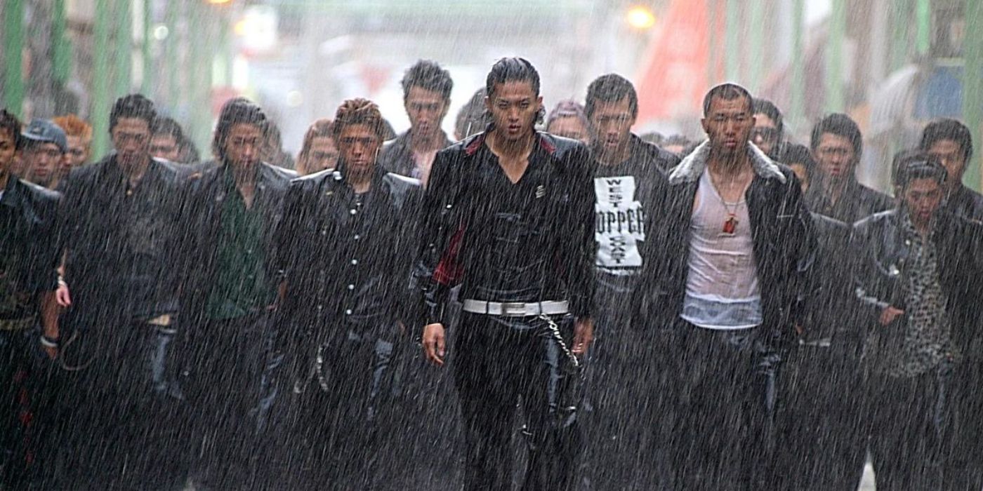 Shun Oguri leading a large group of men while rain pours on them in Crows Zero