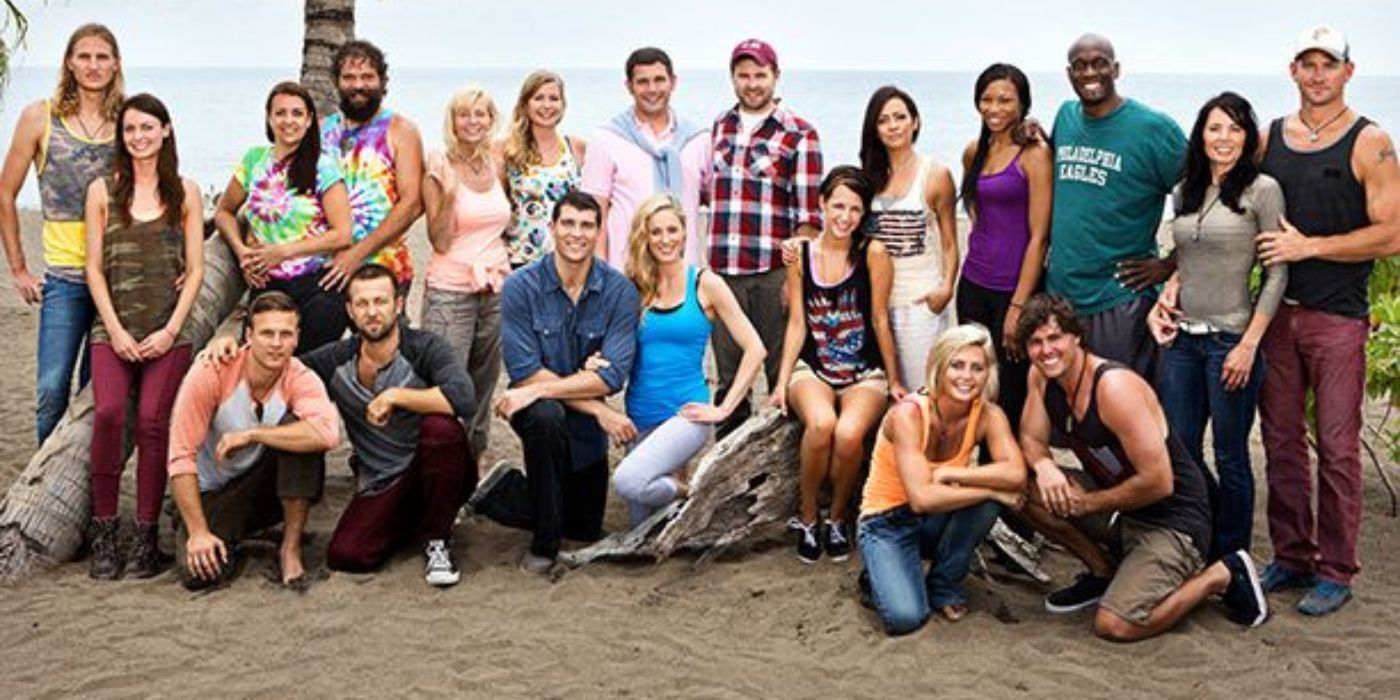 The contestants of Survivor: Blood vs Water pose on a beach and smile at the camera.