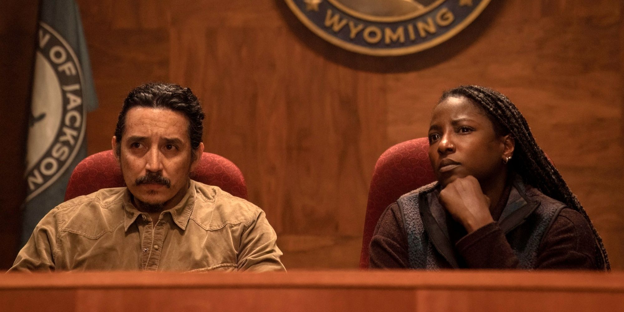 Gabriel Luna as Tommy and Rutina Wesley as Maria sitting at a community meeting in The Last of Us Season 2