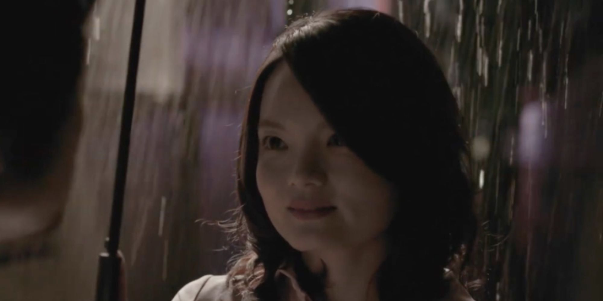 Melanie, played by actress Wei-Yi Lin, stands smiling under an umbrella while rain pours down around her in The Very Last Day.
