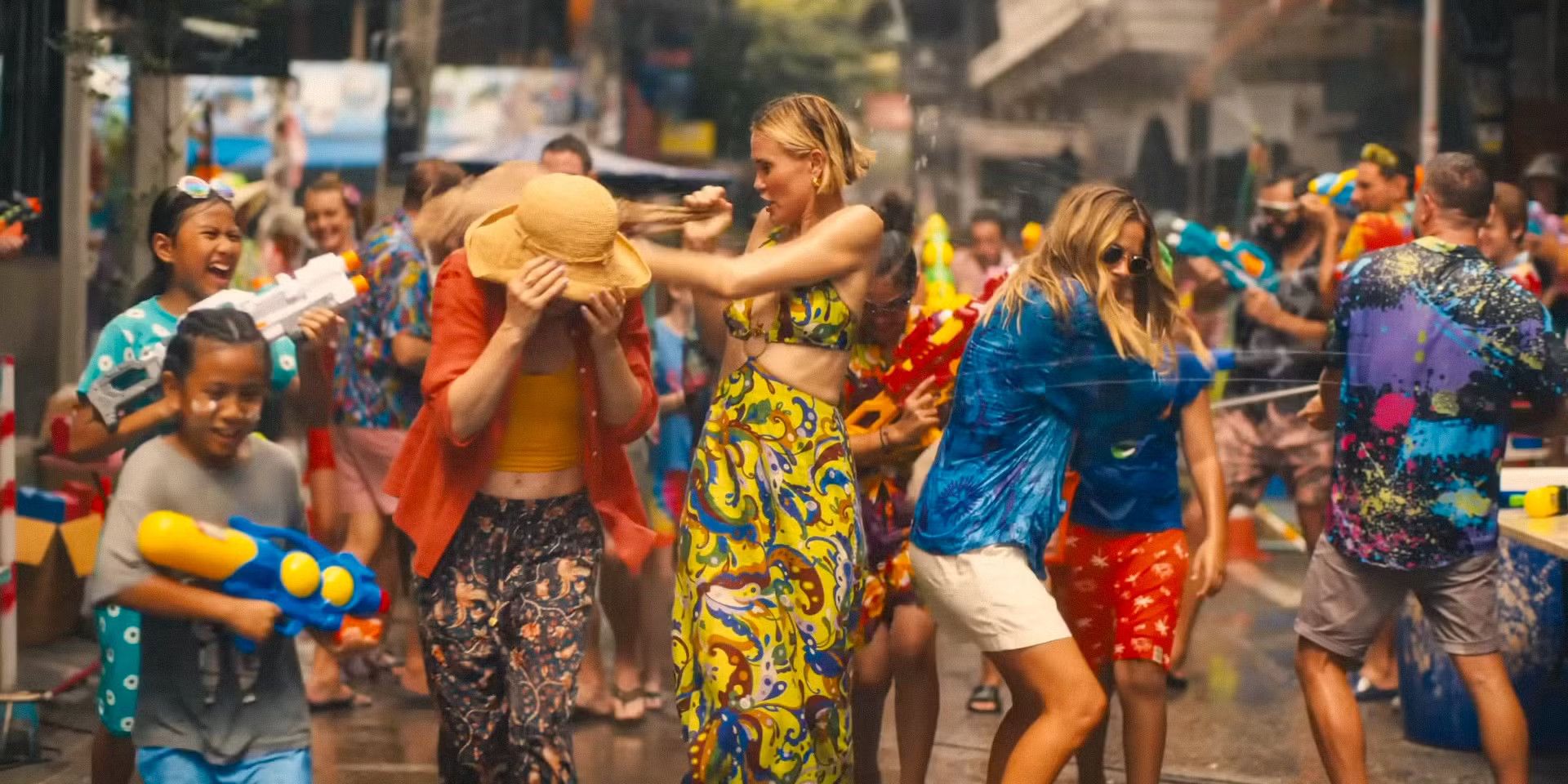 Jaclyn, Kate, and Laurie get shot with multiple water guns as they walk down a street in The White Lotus.