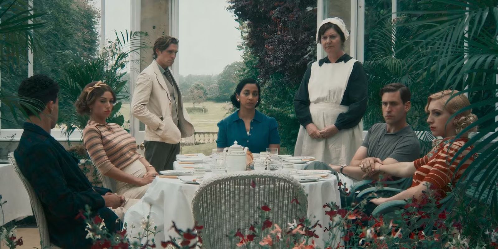 The main cast of Towards Zero 2025 sitting at a table in the garden.