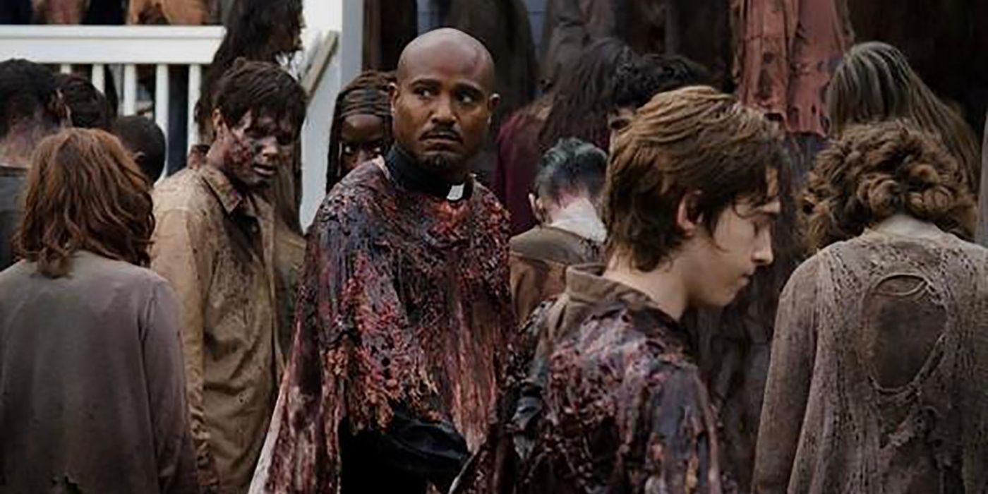 Gabriel wears a cloak made of walker guts and walks amidst a crowd of zombies in The Walking Dead.