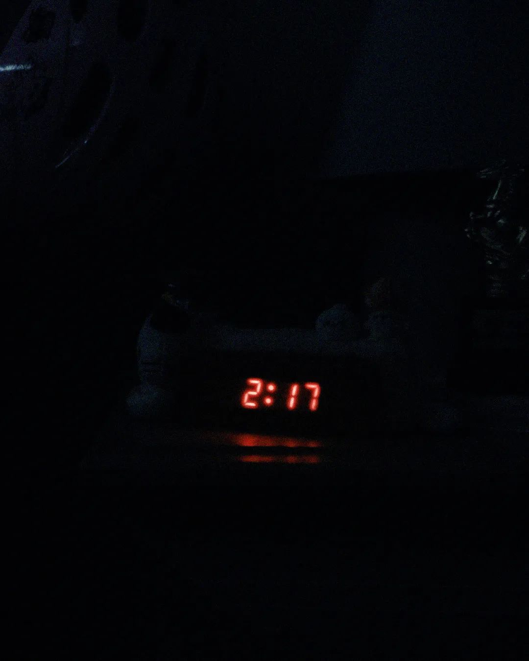 An alarm clock in a dark room set to 2:17 in Weapons