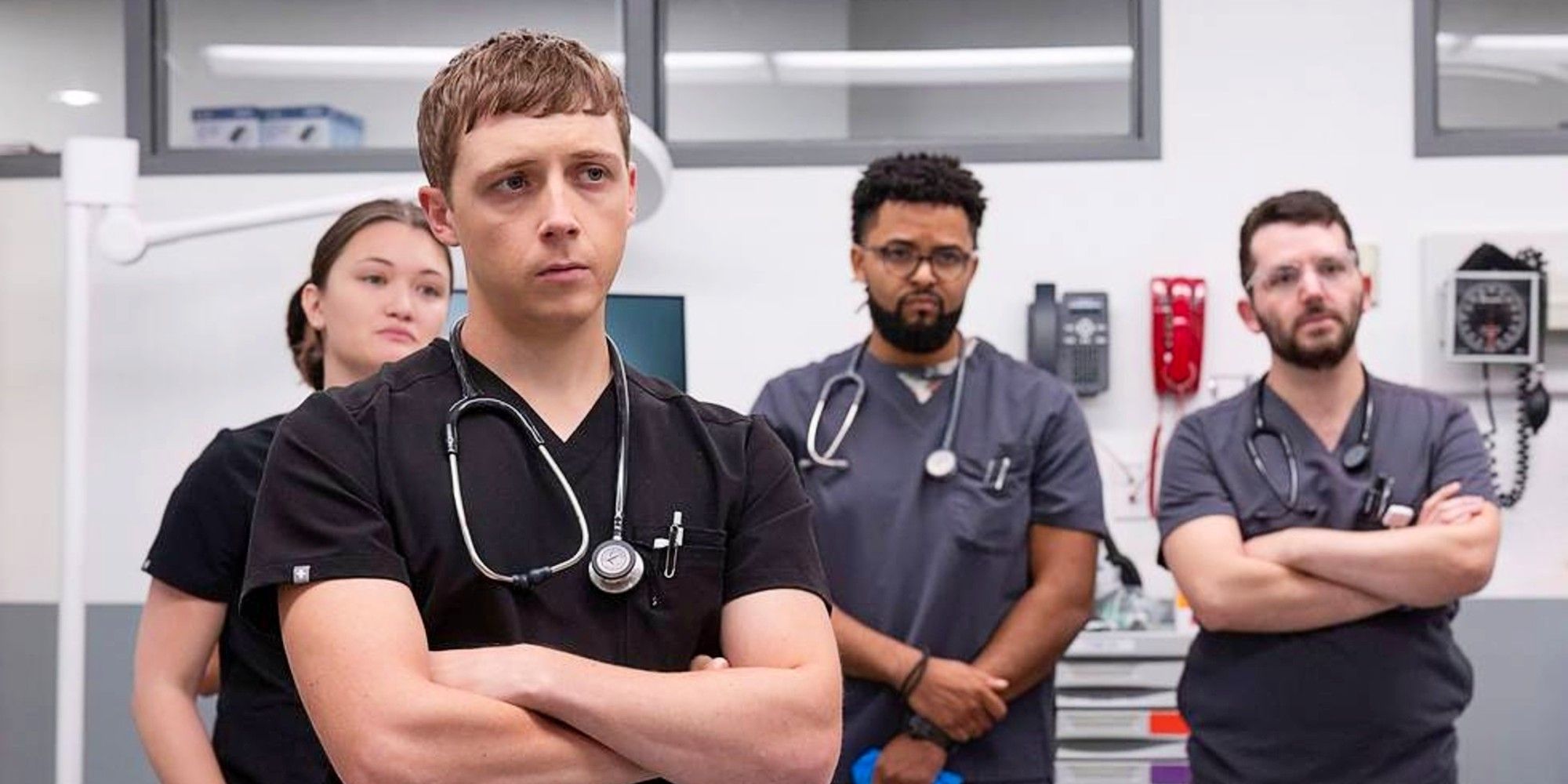 Whitaker and others stand in a hospital and look unamused in The Pitt Season 1.