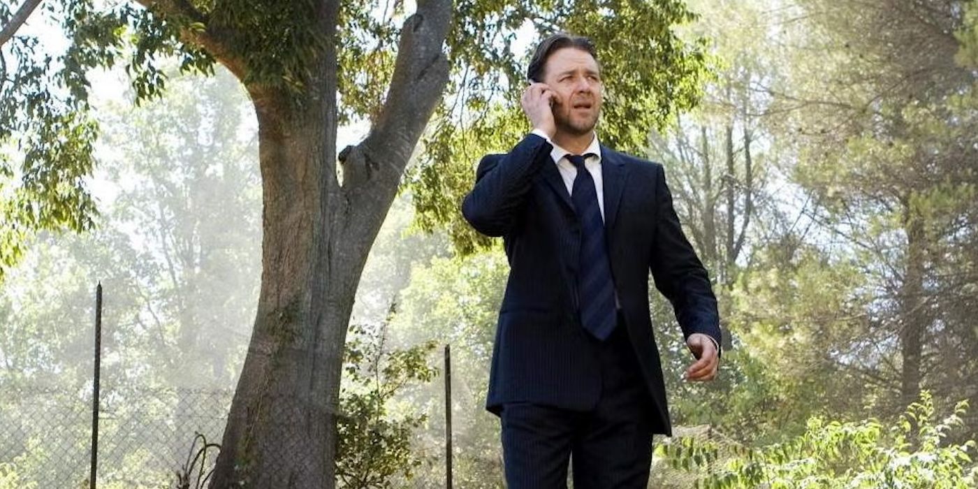 Russell Crowe in a suit and tie talking on a phone outside with trees behind in A Good Year.