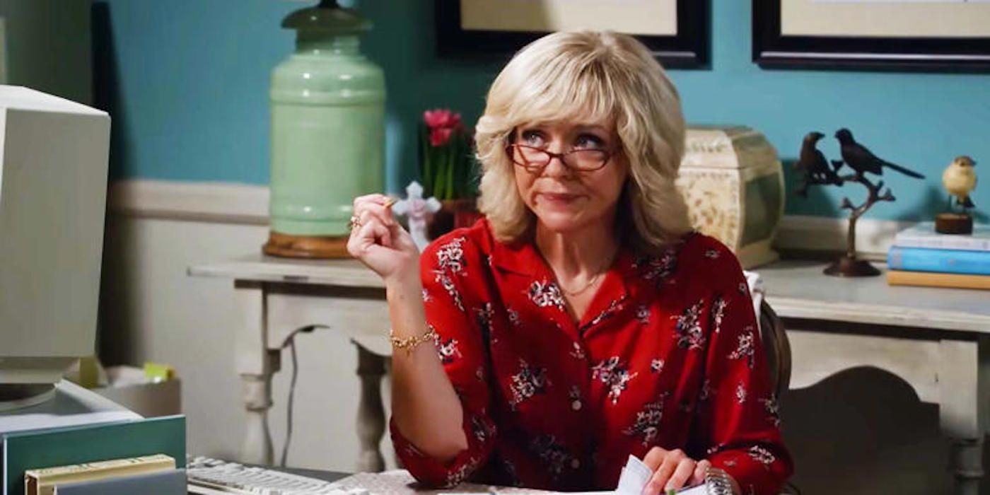 Audrey (Rachel Bay Jones) dá olhar de desaprovação por trás dos óculos sentados em sua mesa no primeiro casamento de Georgie & Mandy.