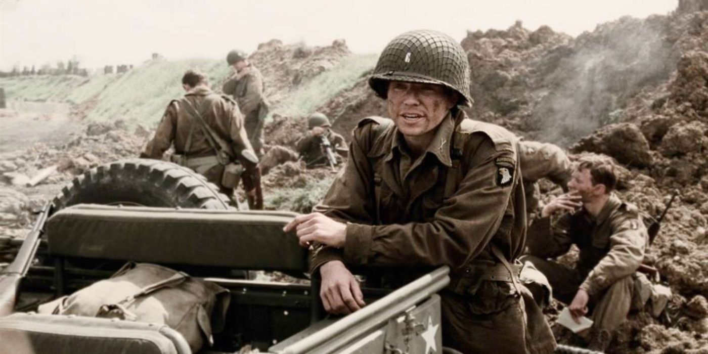 David Nicolle dressed as a soldier leans on the back of a vehicle with a helmet on in Band of Brothers.