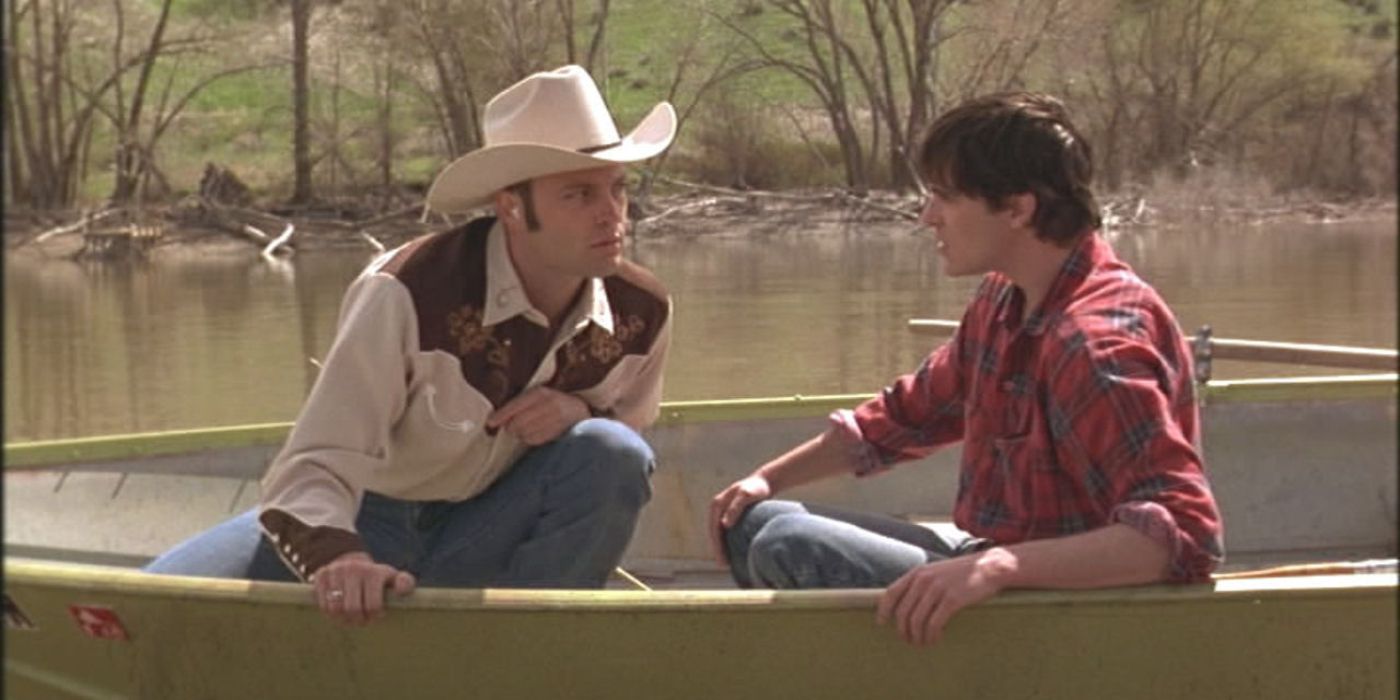 Vince Vaugh in a cowboy hat and Joaquin Phoenix in a boat on a body of water in Clay Pigeons.