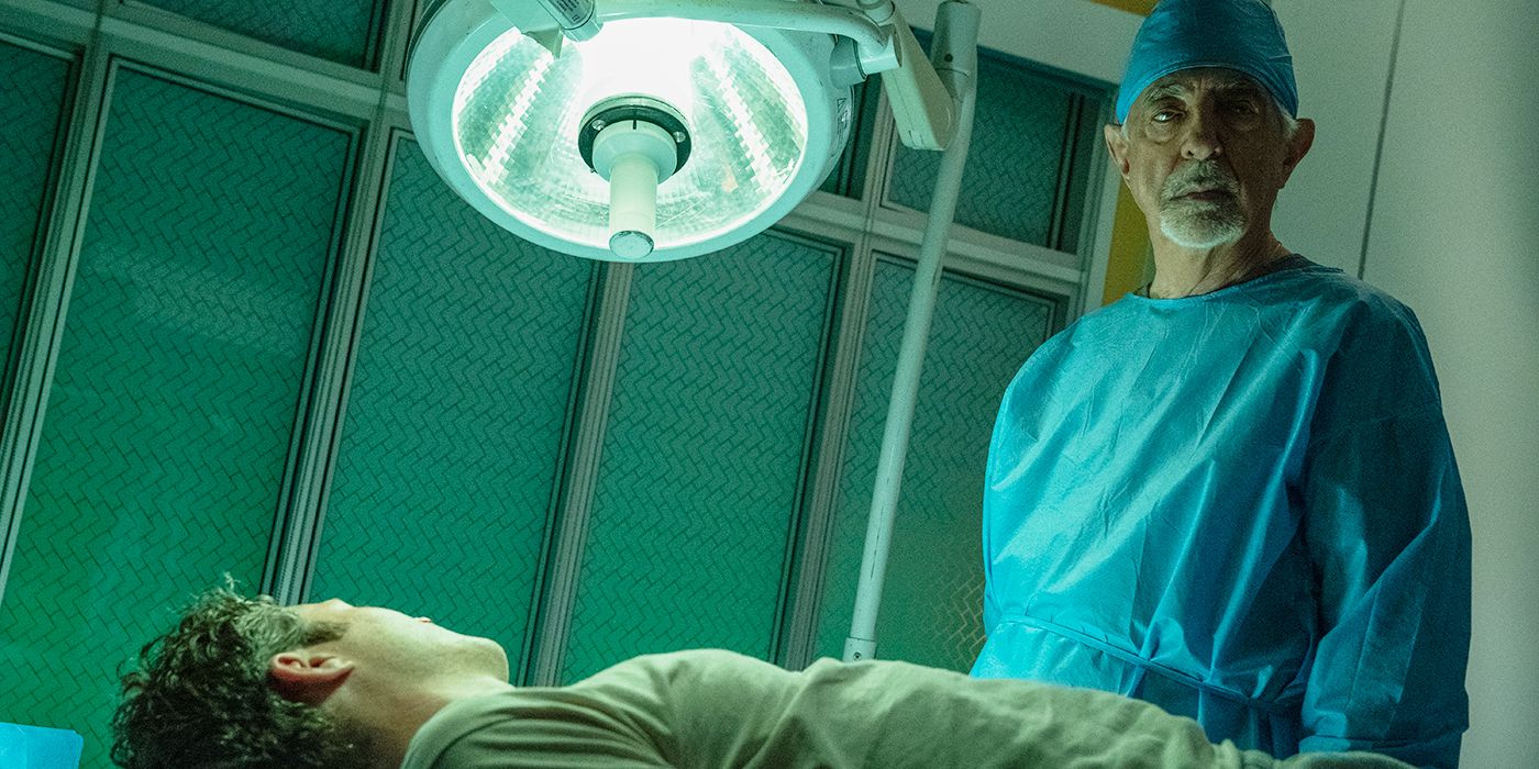 Joe Mantegna in scrubs standing over Zach Gilford in Criminal Minds