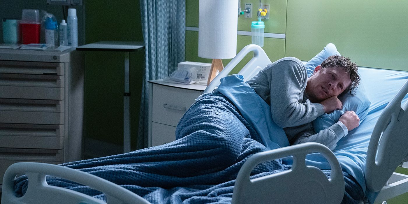 Zach Gilford lying on his side in a hospital bed in Criminal Minds