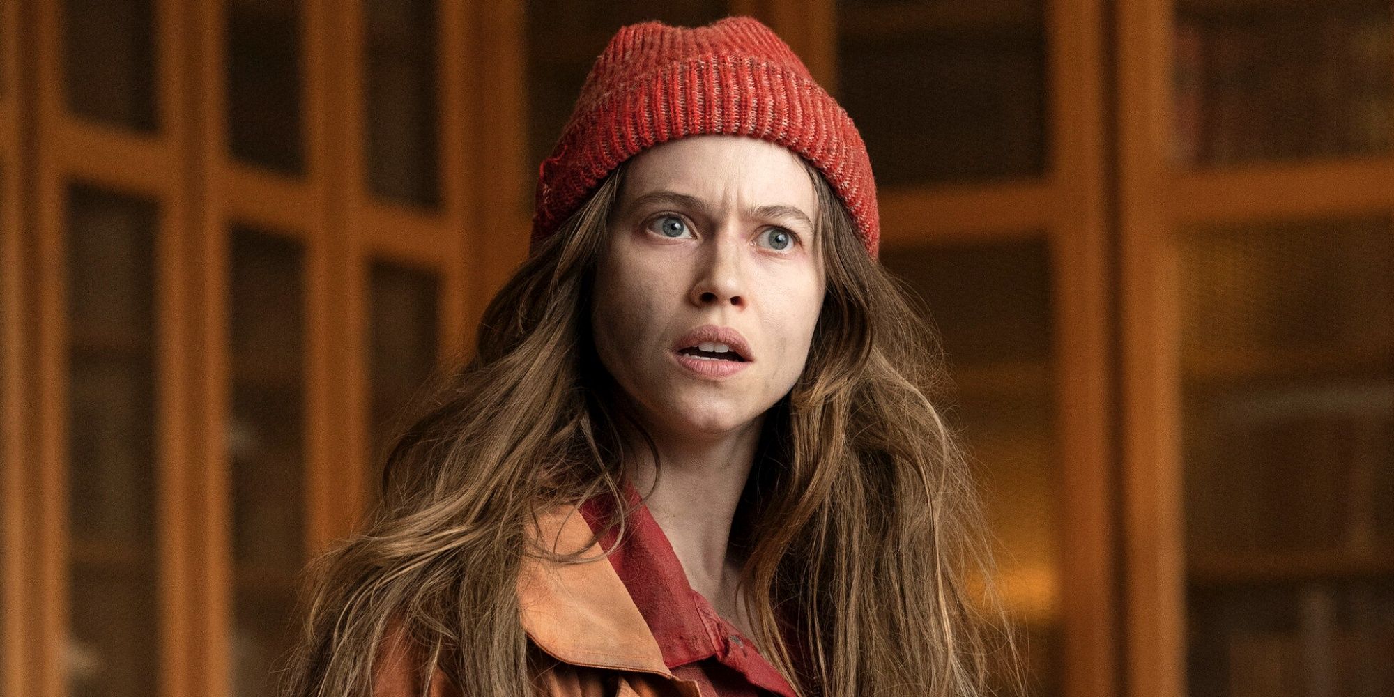 Lou de Laâge as Cheyenne looking surprised in a brick colored knit hat and orange coat in Étoile