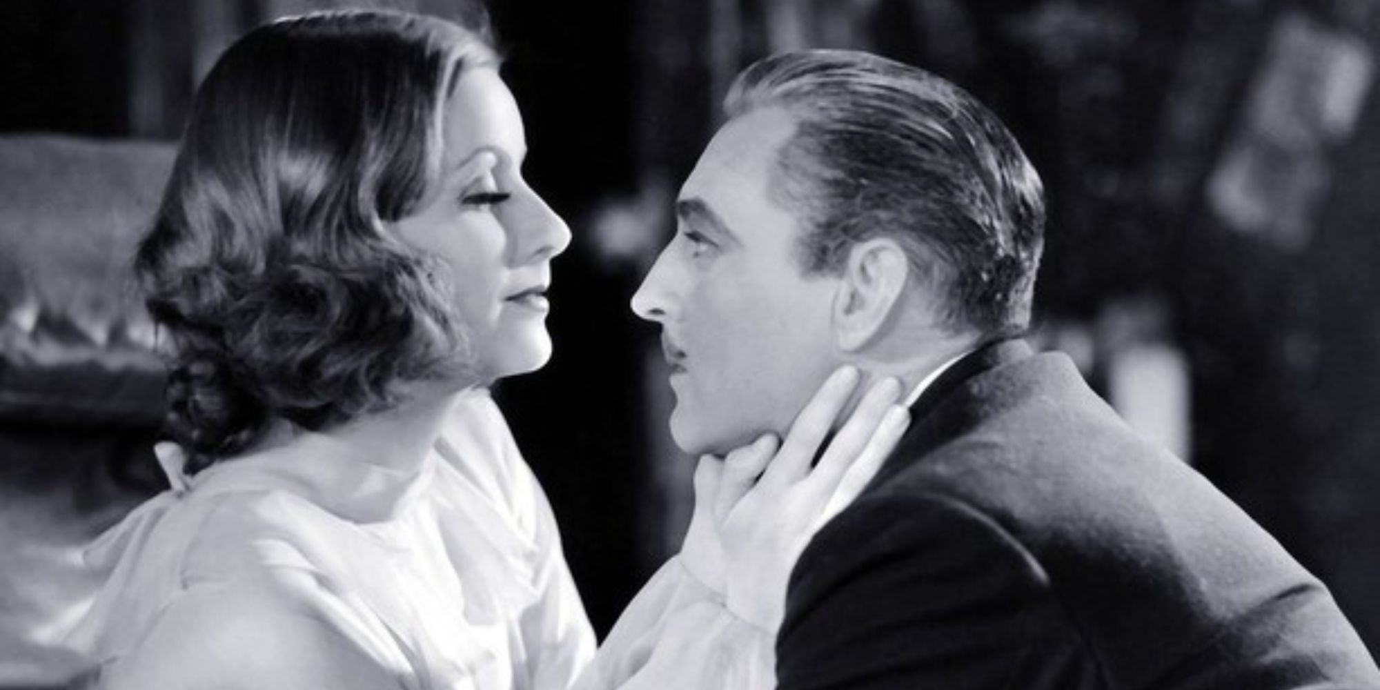 Greta Garbo looking at John Barrymore who sits closely across from her in Grand Hotel (1932).