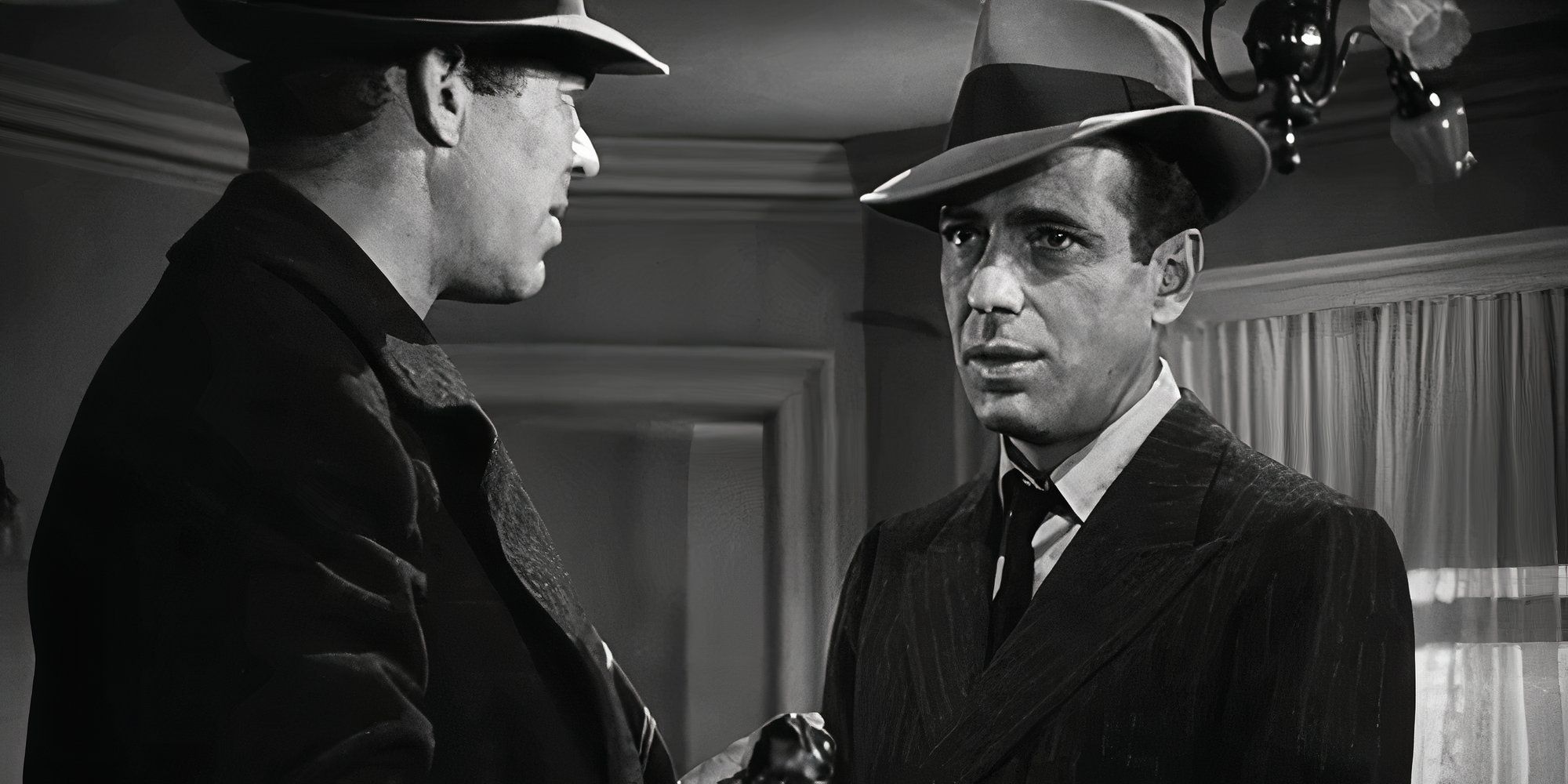 Humphrey Bogart as Sam Spade talking to another man in the final scene of The Maltese Falcon (1941).