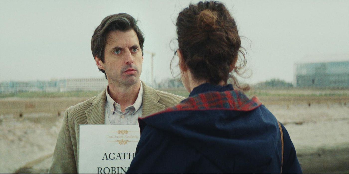 Charlie Anson holding a sign with a name on it looking at a woman with brown hair in Jane Austen Wrecked My Life