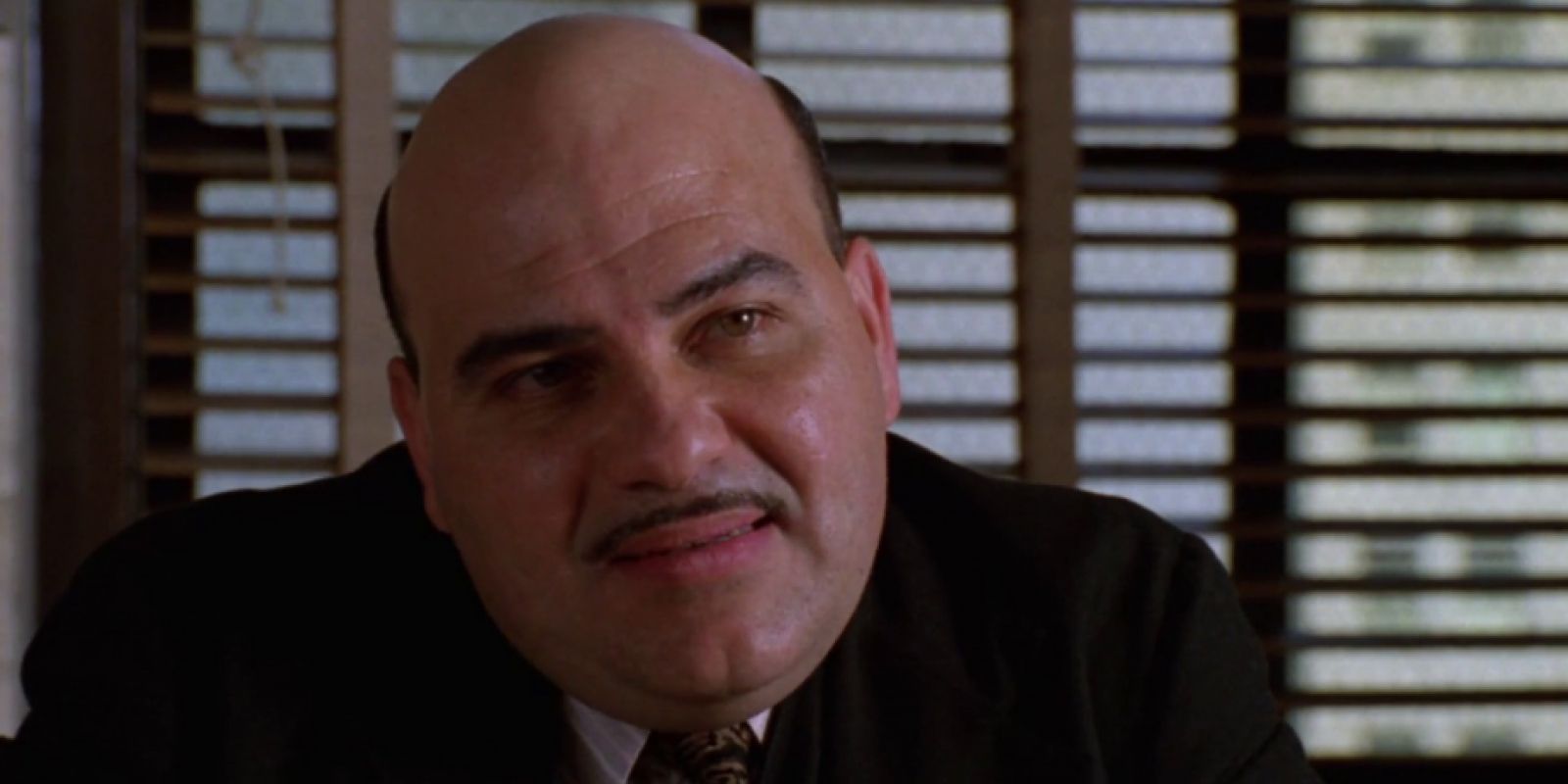 Jon Polito sits in front of a window with blinds in Homicide: Life on the Street.
