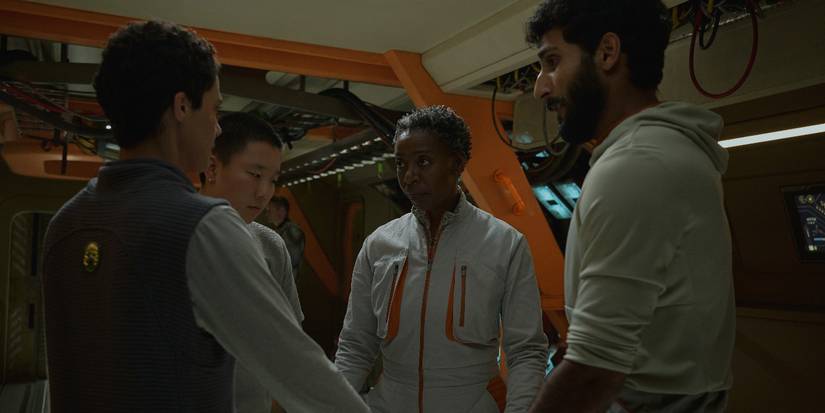 Team members holding hands in a circle in Murderbot Episode 3, including Noma Dumezweni as Mensah, Akshay Khanna as Ratthi, Pin-Lee, Sabrina Wu and Arada Tattiawna Jones