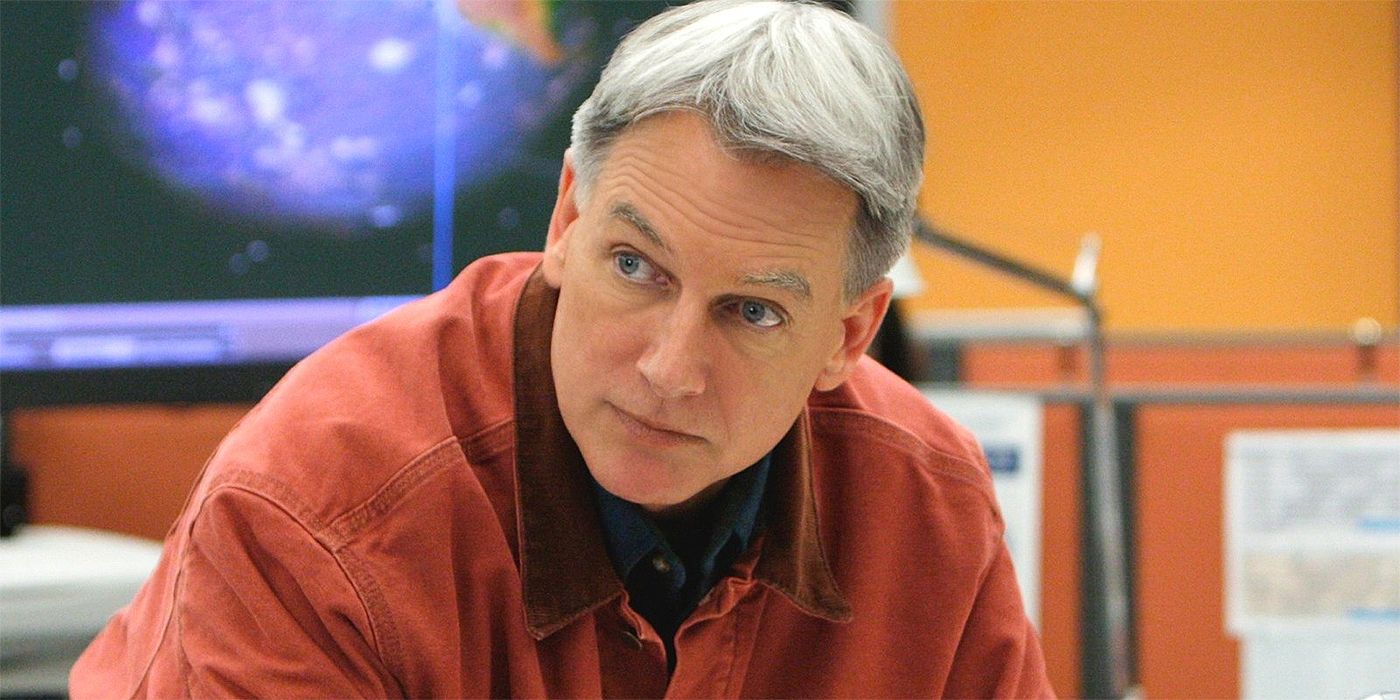 Mark Harmon as Gibbs looking over at someone while hunched over a desk in NCIS