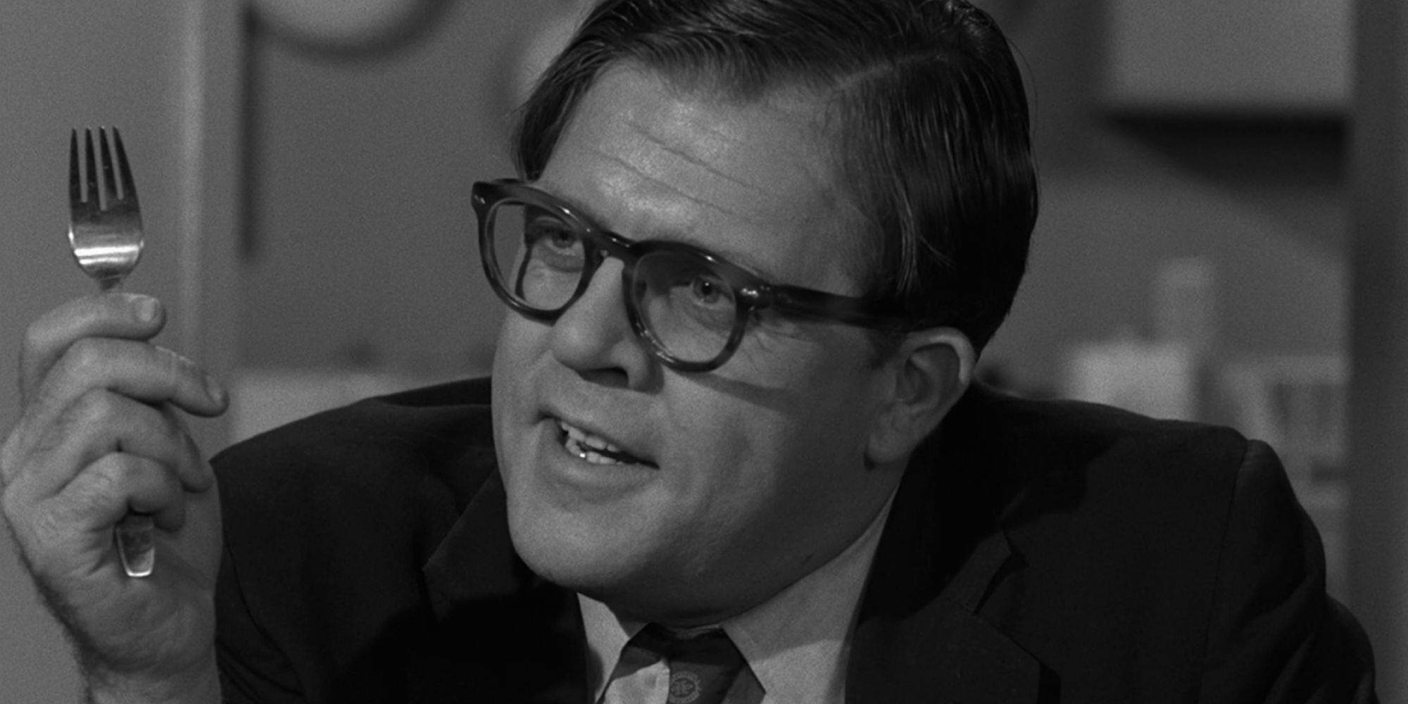 Pat Hingle sitting down and holding up a fork in one of his hands in The Twilight Zone episode The Incredible World of Horace Ford
