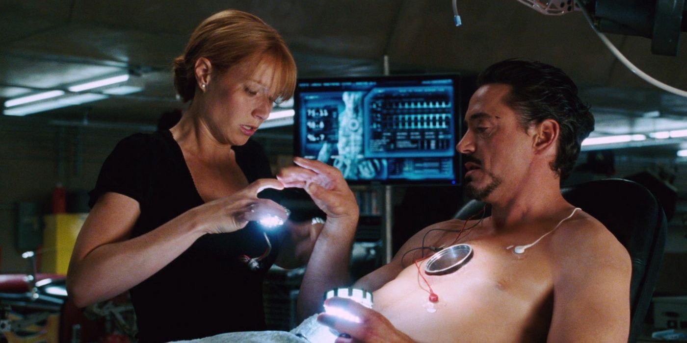 Pepper holding the arc reactor in front of Tony, who is hooked up to medical monitors in Iron Man.