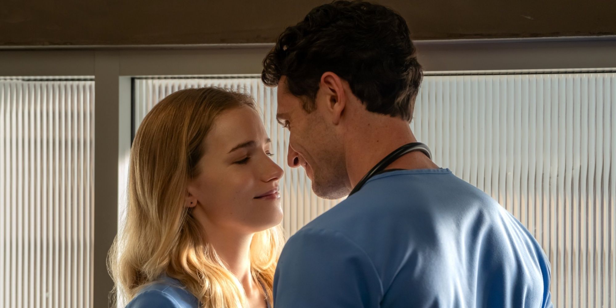 Willa Fitzgerald as Danny about to be kissed by Colin Woodell as Phillips in their scrubs in Pulse