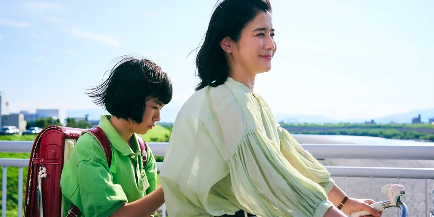 Fuki (Yui Suzuki) sentado na parte de trás de uma bicicleta atrás de sua mãe, Utako (Hikari Ishida) em Renoir