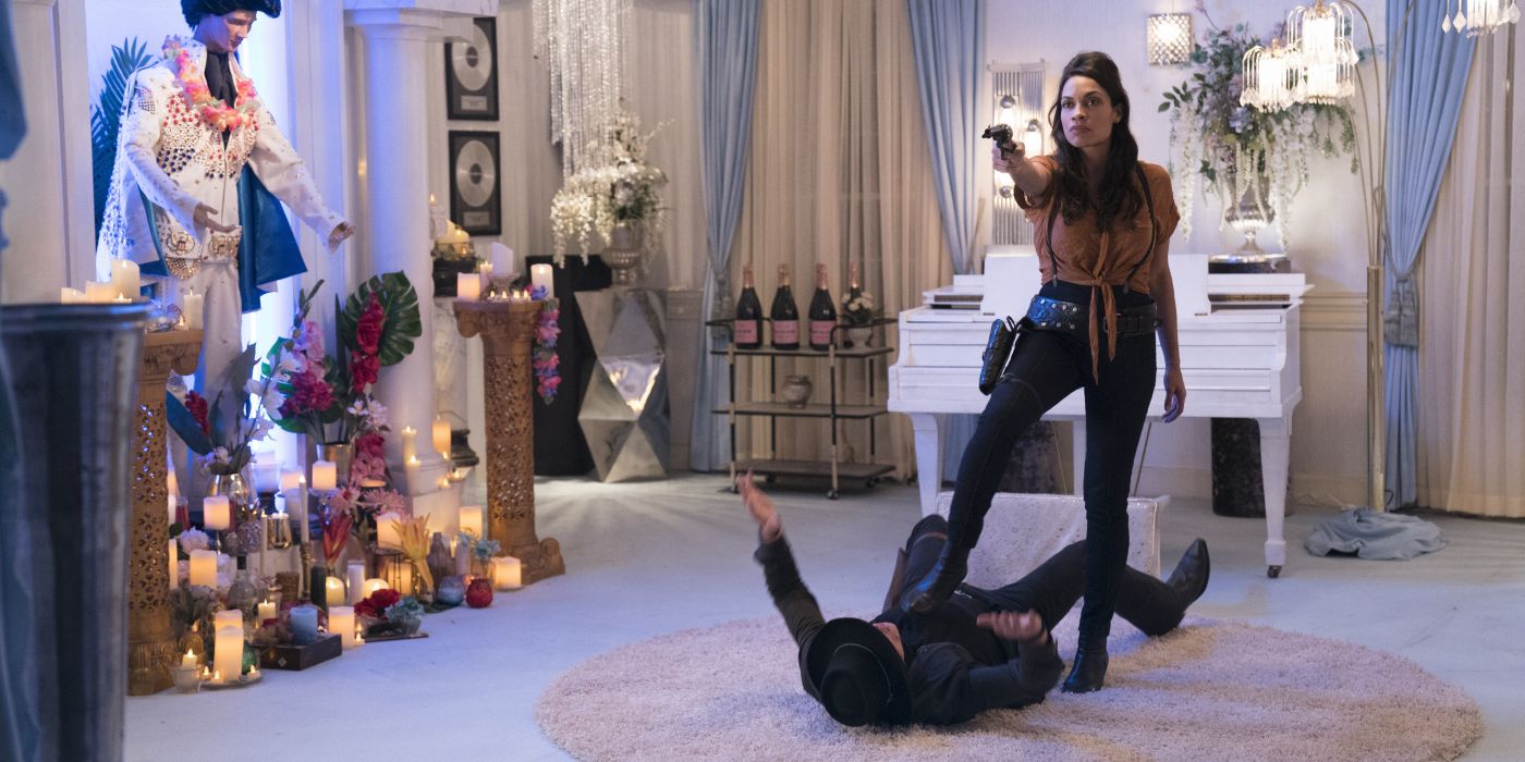 Rosario Dawson stands over someone and points a weapon in front of her in Zombieland: Double Tap.