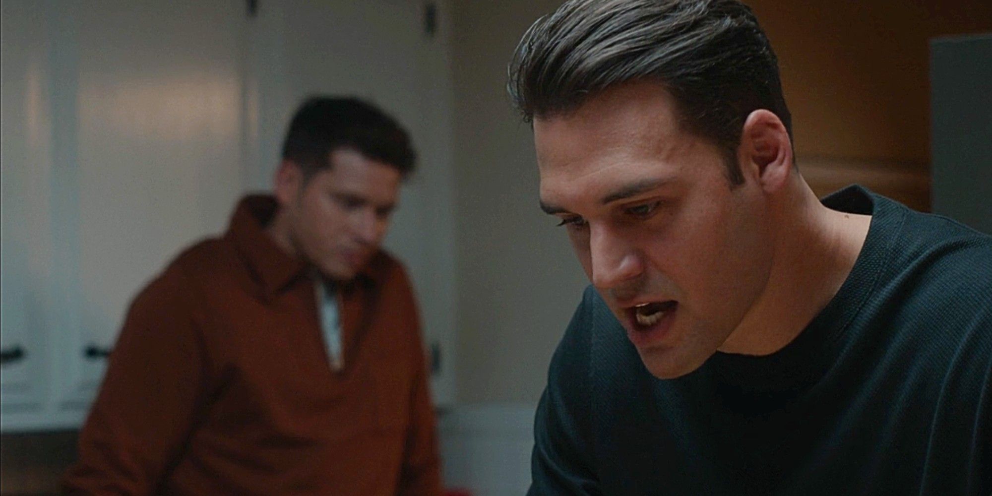 Eddie Diaz looking upset while Buck stands sadly behind him in the kitchen in 9-1-1 Season 8