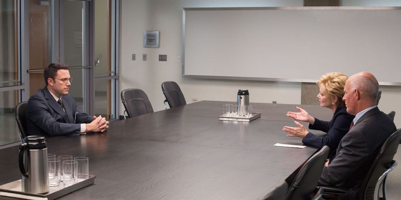Ben Affleck sits across from Jean Smart and Andy Umberger in a business meeting room in The Accountant.