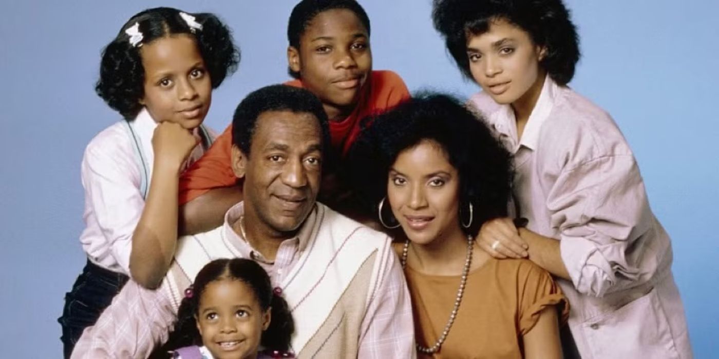 The cast of The Cosby Show pose for a group promo photo against a plain backdrop. 