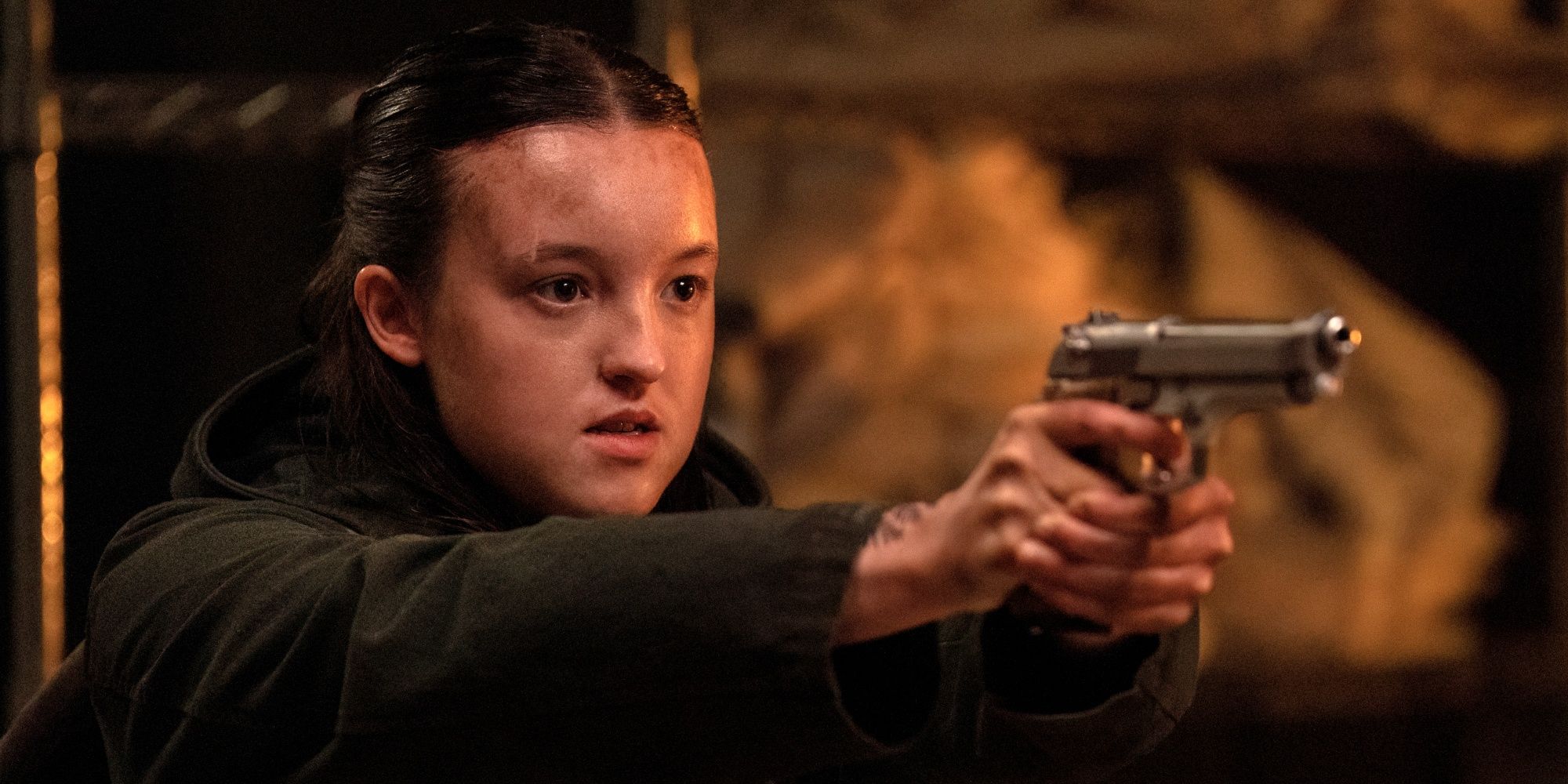 Bella Ramsey as Ellie holding Nora at gunpoint and looking angry in The Last of Us Season 2.