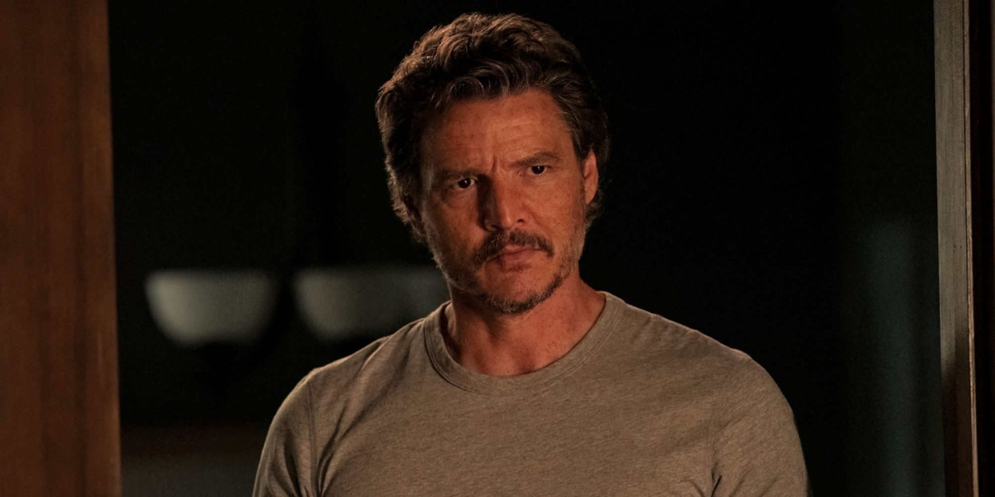 Pedro Pascal as Joel in a grey t-shirt looking serious in The Last of Us Season 2