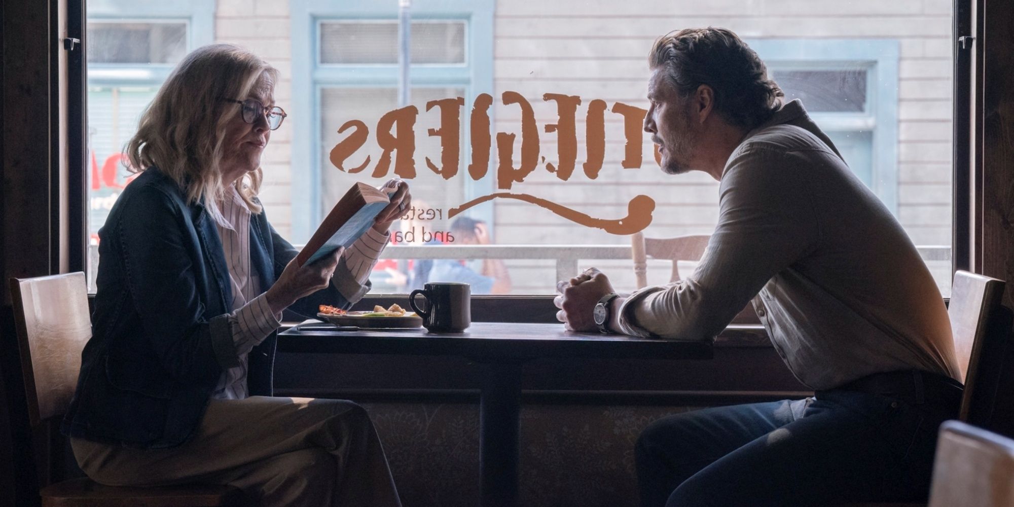 Pedro Pascal as Joel sitting at a diner table across from Catherine O'Hara as Gail in The Last of Us Season 2