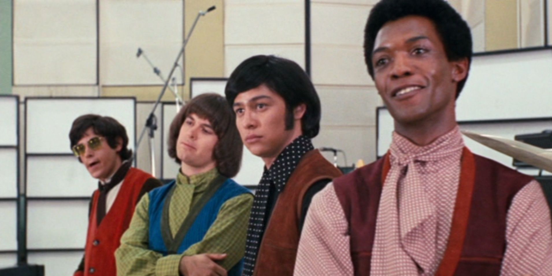 A group of rockstars stand near an empty stage and look at something off-camera in The Phynx, 1970.