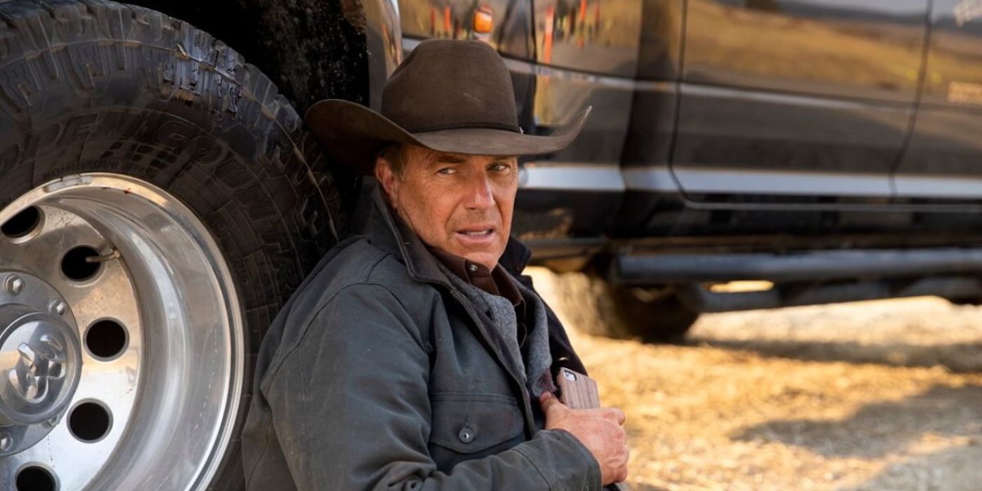 Kevin Costner as John Dutton sitting, leaning on his car wounded in Yellowstone Season 4, Episode 1.